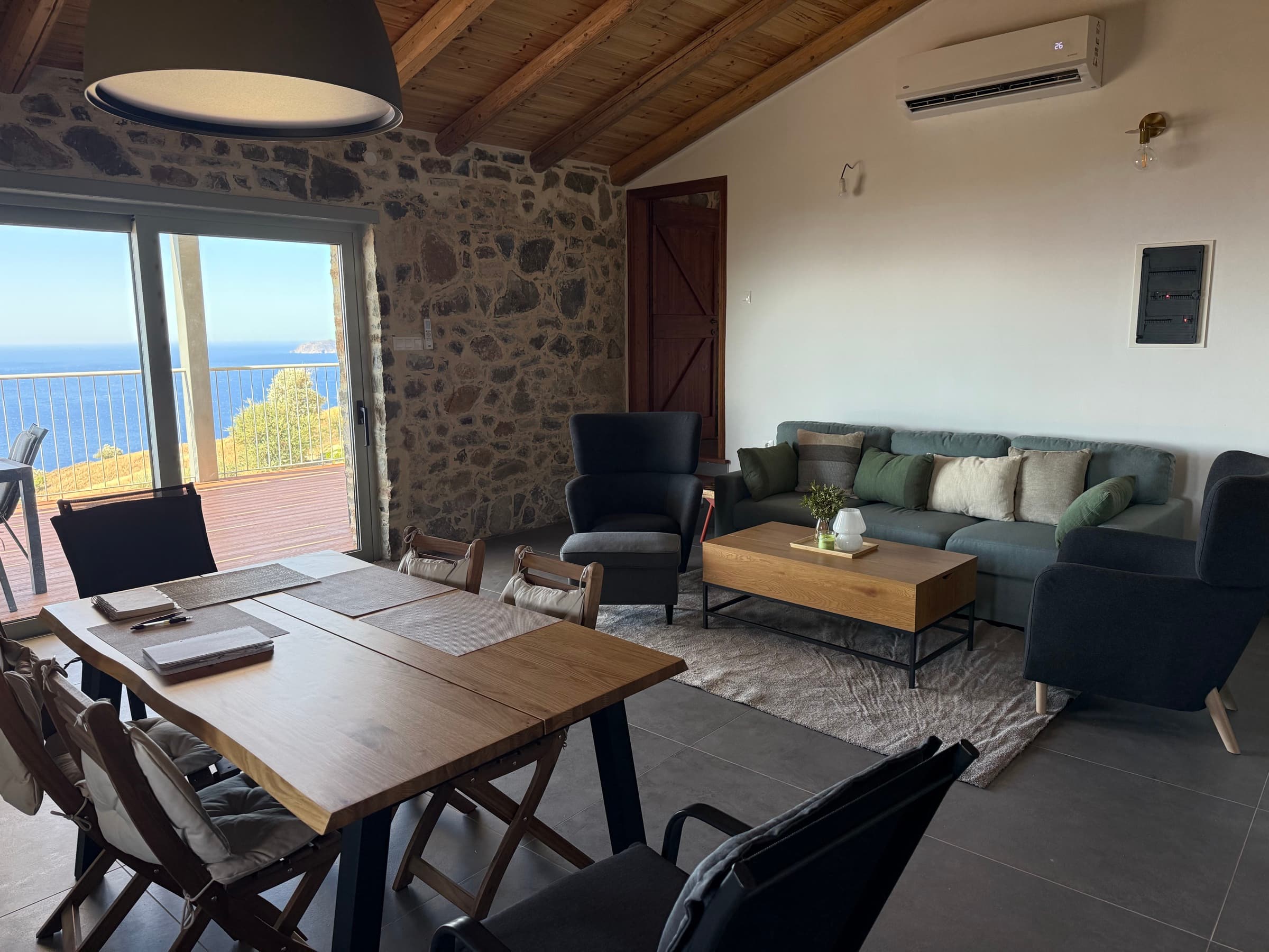 Living room with stone wall, sofa and dining table, the Libyan Sea through the glass doors
