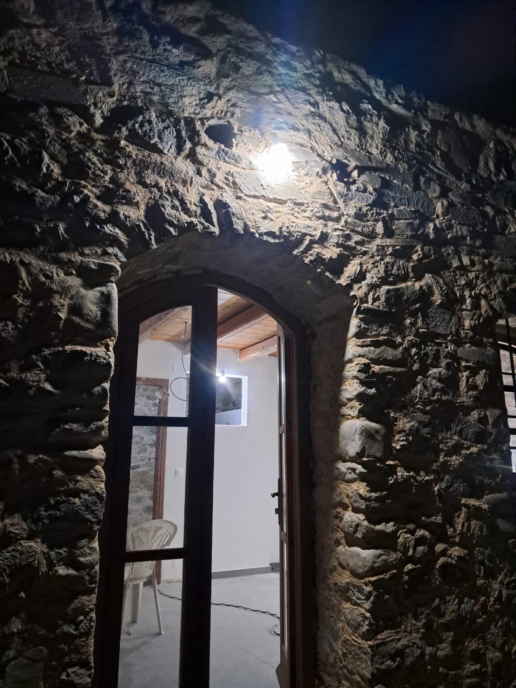 Stone arched doorway at night, hand-laid masonry lit from above