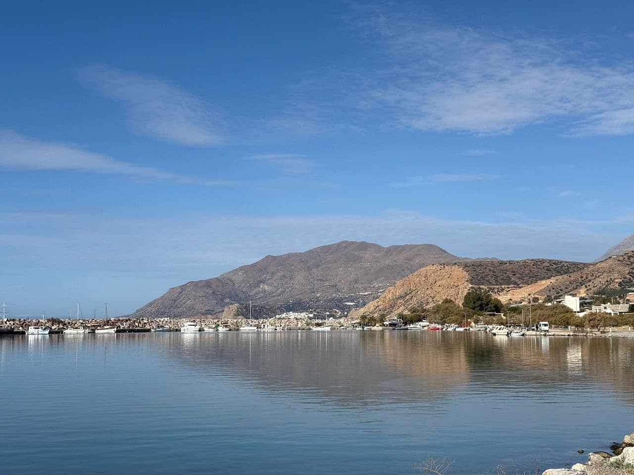 Fishing boats at the harbour wall, the water flat, the mountain behind